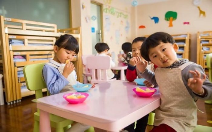 Children eating at a table in a classroom.