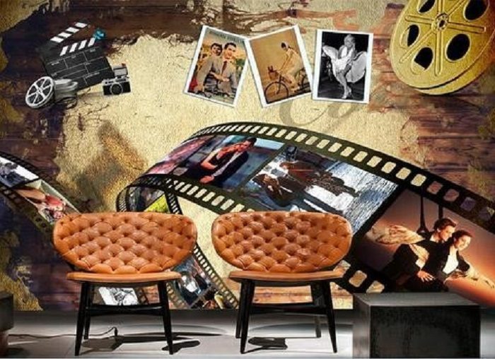 A living room with chairs and a movie clap wall mural.