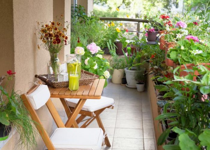 A small balcony with a table, chairs, and potted plants.