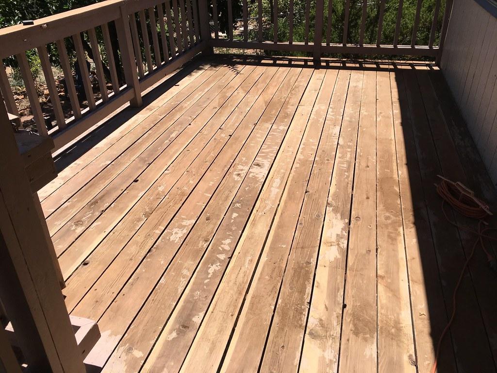 A power washer is being used to clean a wooden deck.