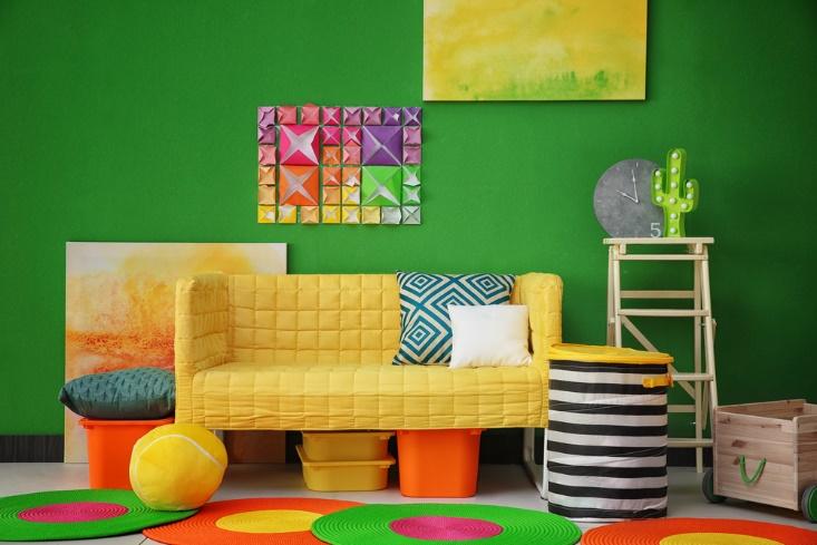 A trendy room with a colorful yellow couch and vibrant pillows.