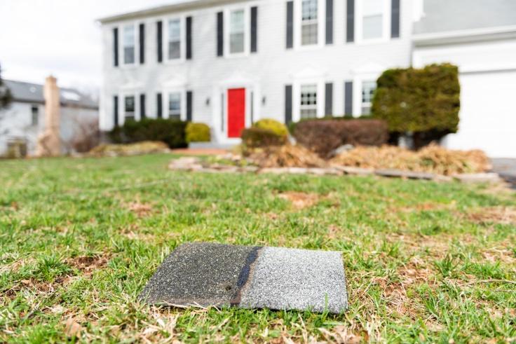 A piece of slate is sitting on the grass in front of a house, indicating exterior maintenance.