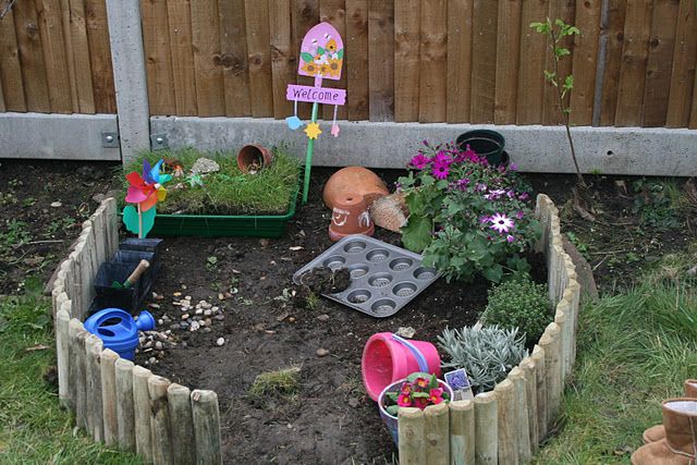 A small garden with a wooden fence and plants, perfect as a playground for kids.