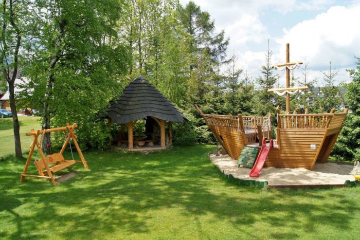 A playground for kids with a wooden pirate ship and swings.