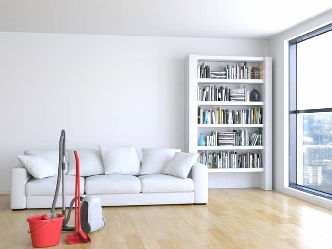 A living room with a white couch and a mop.