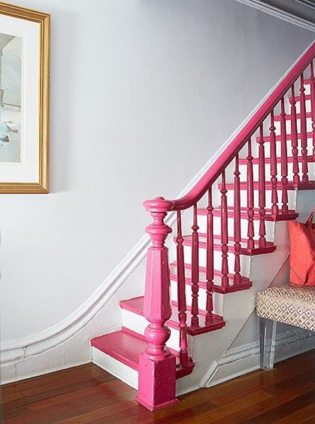 A staircase with a pink handrail design and a bench.