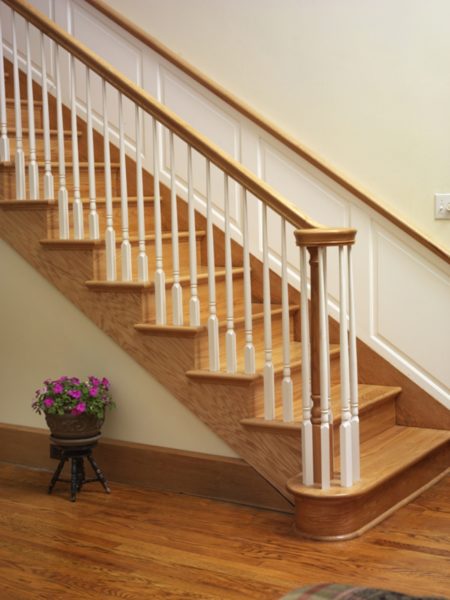 A wooden staircase with a white handrail.