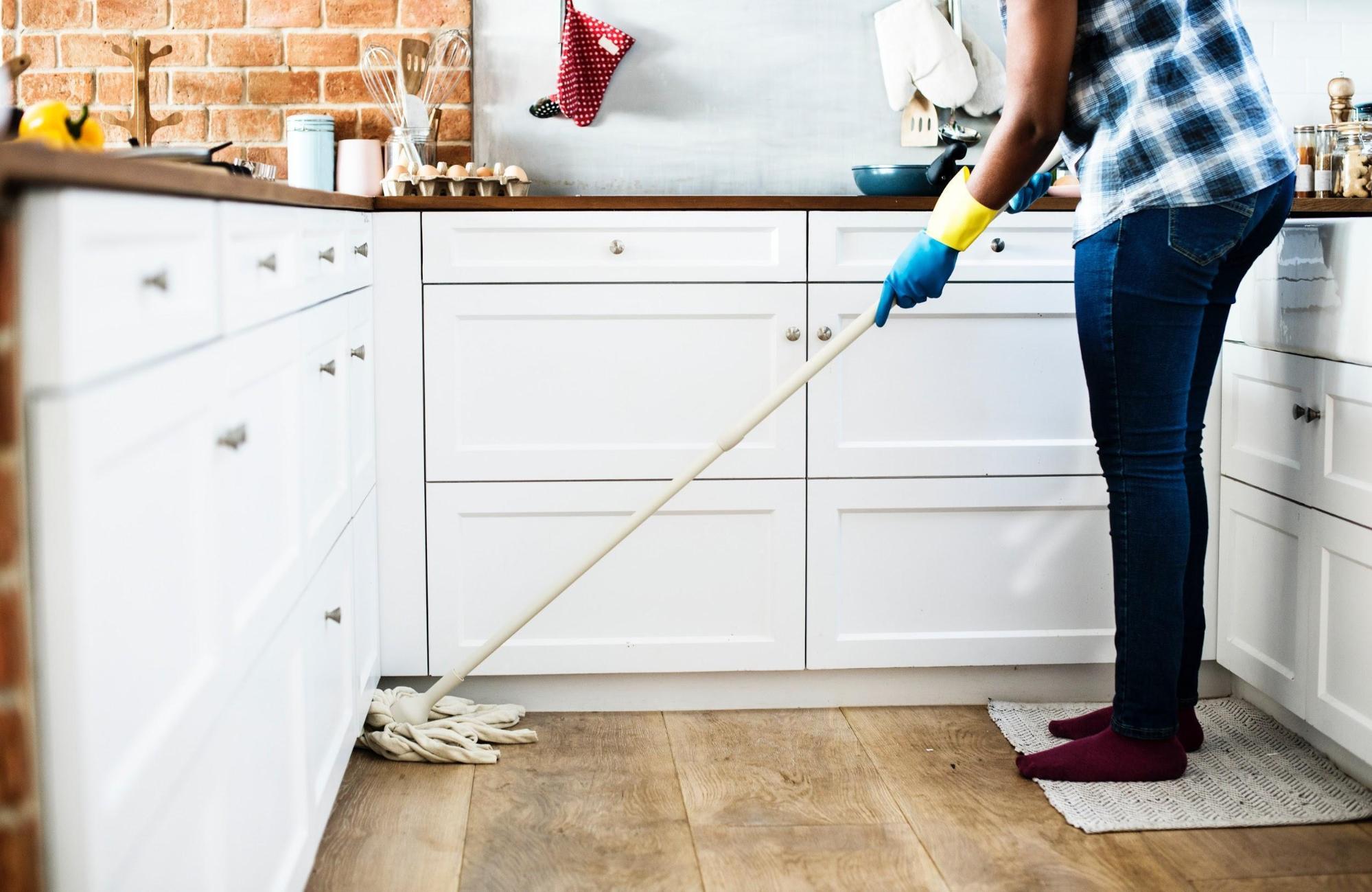 A woman using a mop for green cleaning in the kitchen.