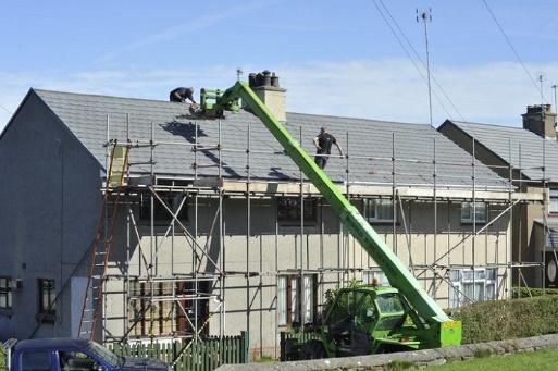 A crane is being used to install scaffolding on a house.