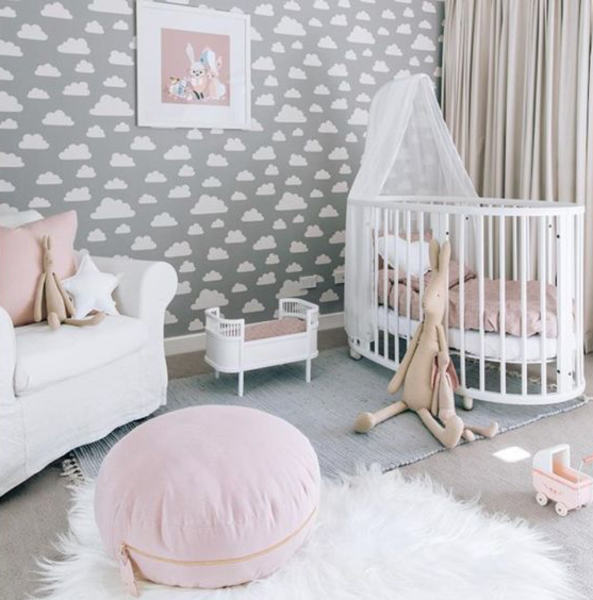 Pink and grey nursery design with cloud wallpaper.