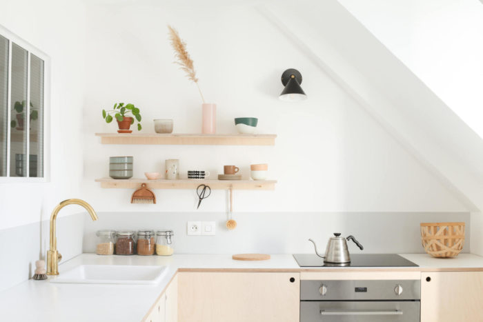 A kitchen designer incorporates wooden shelves and a sink into a white kitchen design.
