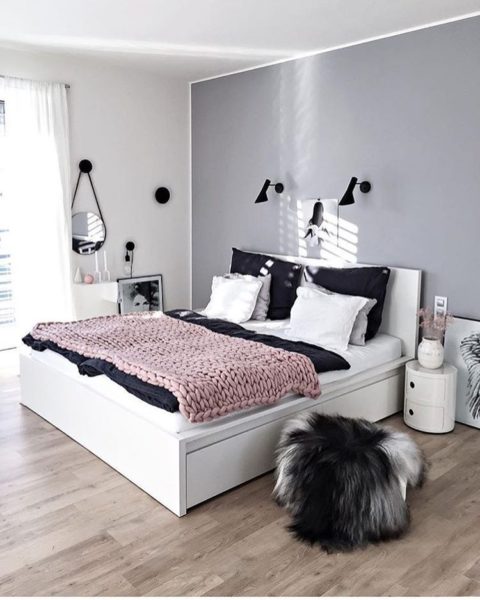 A minimalist bedroom with a white bed and grey walls.