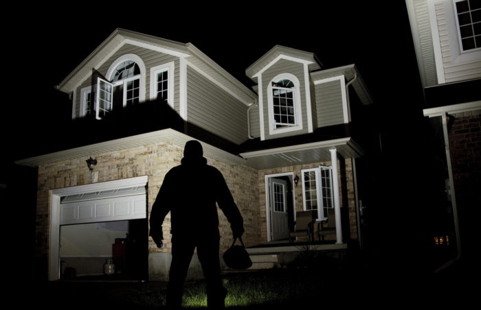 A man enhancing home security by standing in front of a house at night.