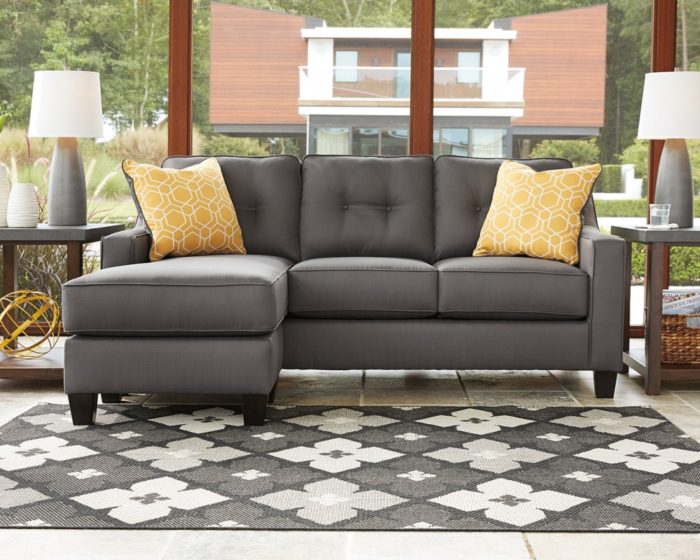 A gray sectional sofa with yellow pillows for trade.