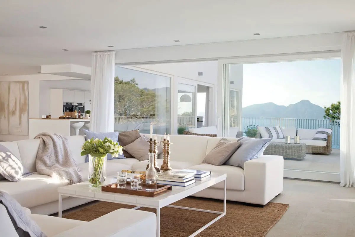 A house with a white living room and a view of the ocean.