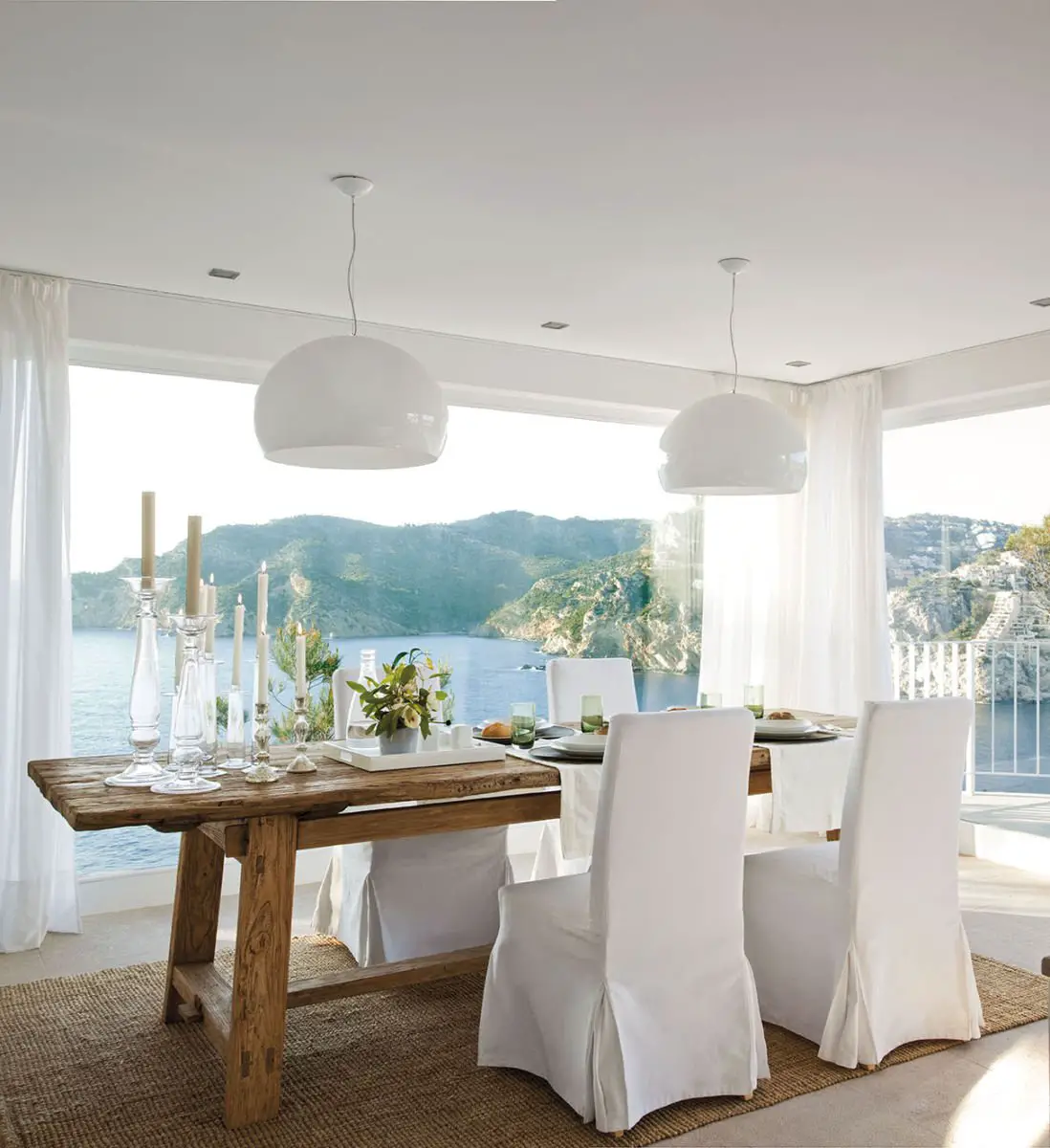 A white dining room in a house with a view of the ocean.
