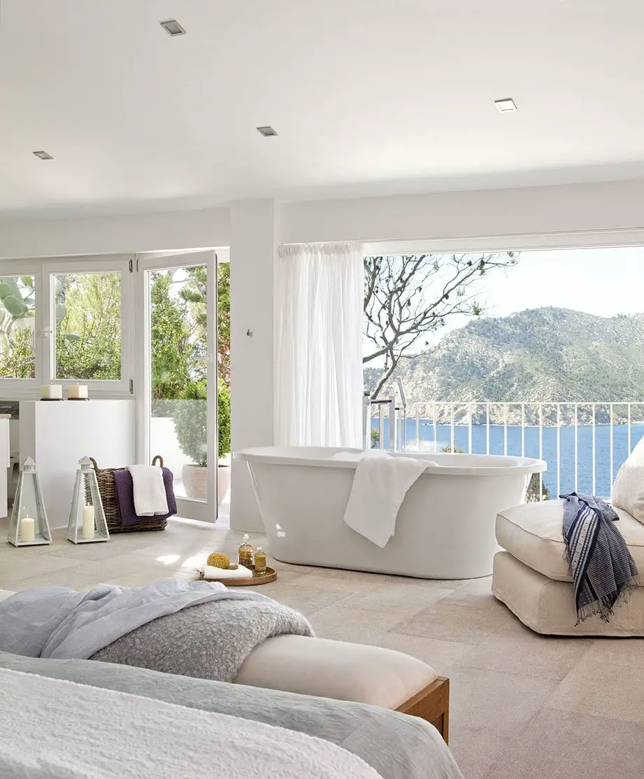 A white bedroom with a view of the ocean in a house.