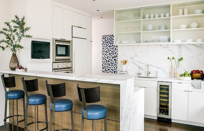 A colorful kitchen with blue stools and a marble counter top.
