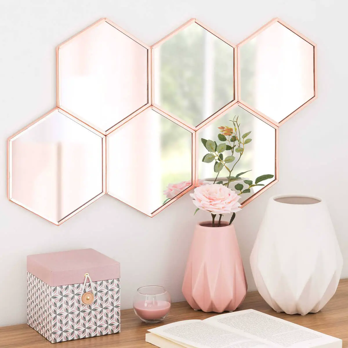 A pink hexagonal mirror on a wall with vases showcasing mirror ideas.
