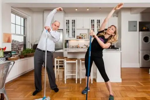 A couple doing exercises in a tidy kitchen.