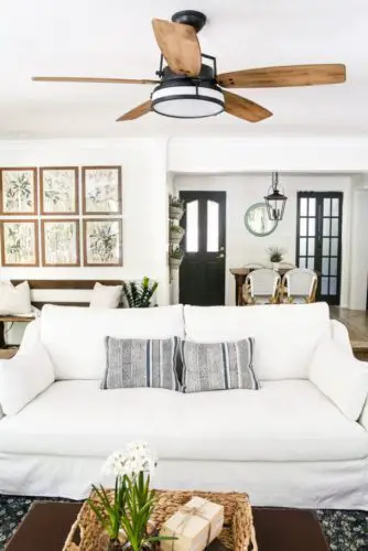A living room with white furniture and a ceiling fan that promotes air circulation of your home.