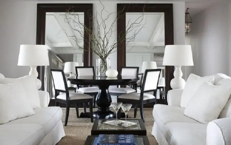 Elegant dining room with white sofas and dark wood table.