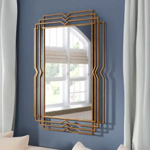 A gold framed mirror on a blue wall that embodies unique mirror ideas.