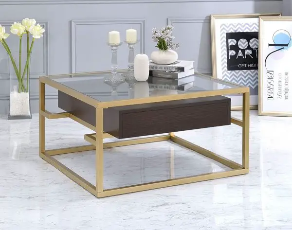 A amazing gold and glass coffee table with a drawer.