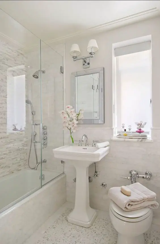 A small white bathroom with a glass shower.