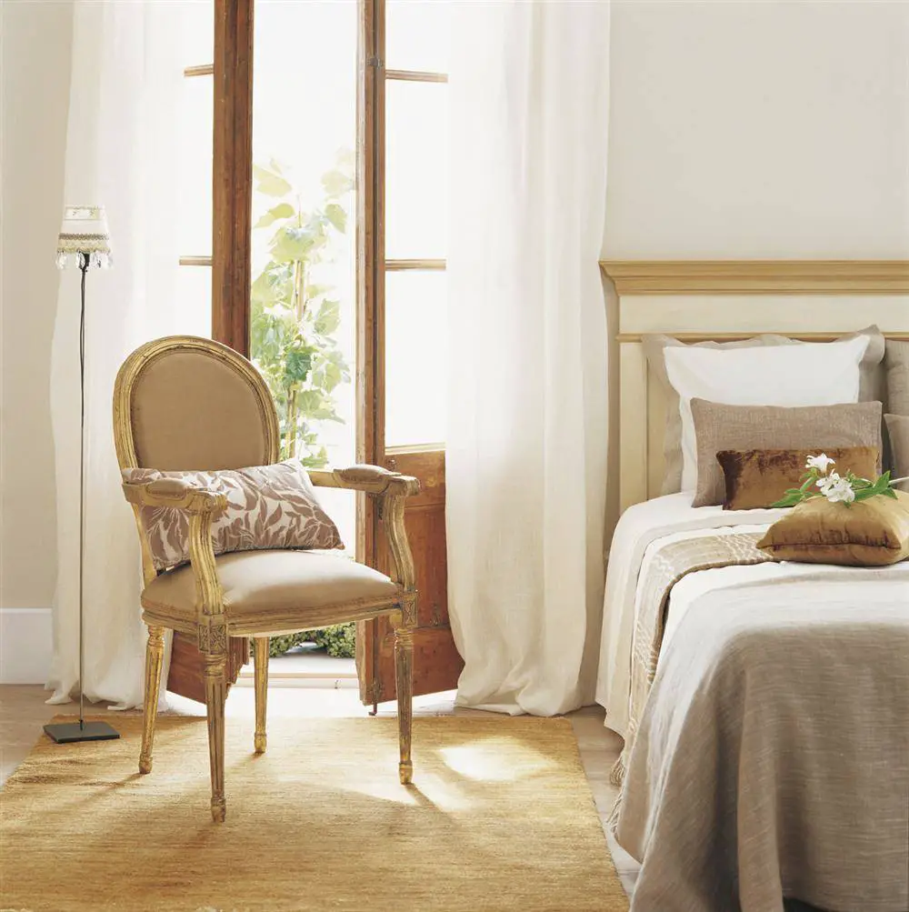 A bedroom with renovated beige walls and a beige chair.