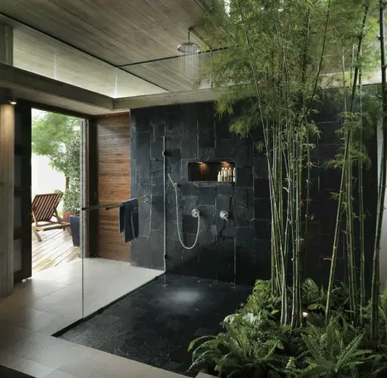 A stylish bathroom featuring a sleek black shower and refreshing bamboo plants.