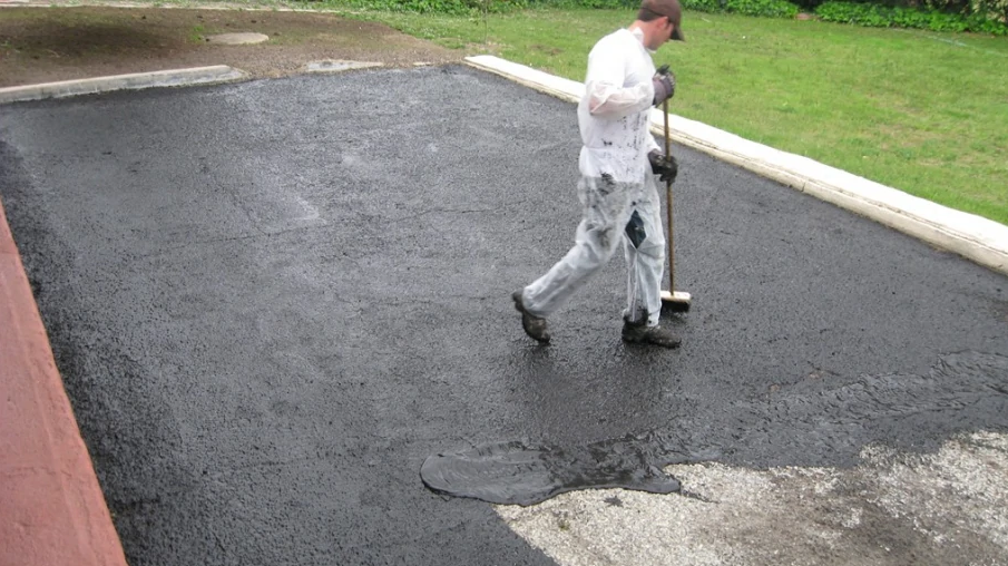 A man is using concrete sealers on a driveway.