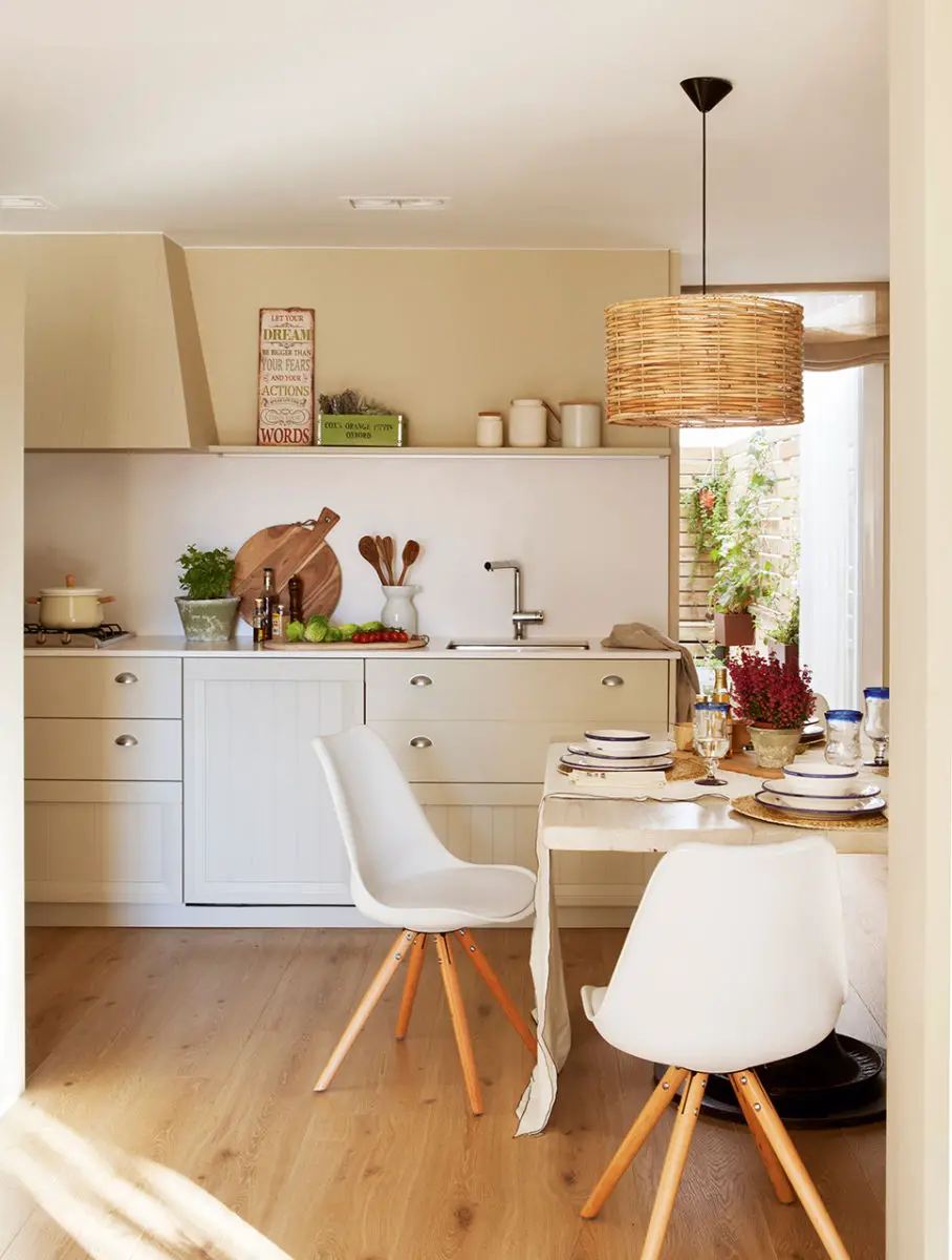 A white kitchen in a house with wooden floors and white chairs.