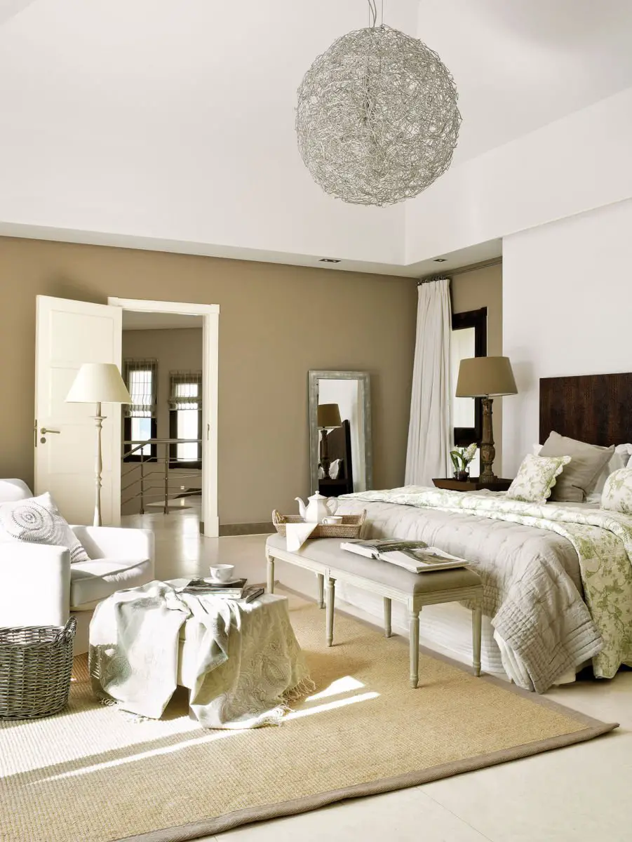 A bedroom with beige walls and a white bed that needs painting.