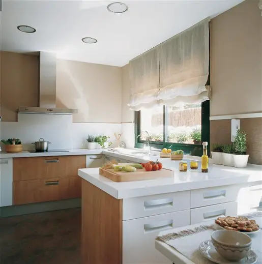 A kitchen design with beige cabinets and white counter tops.