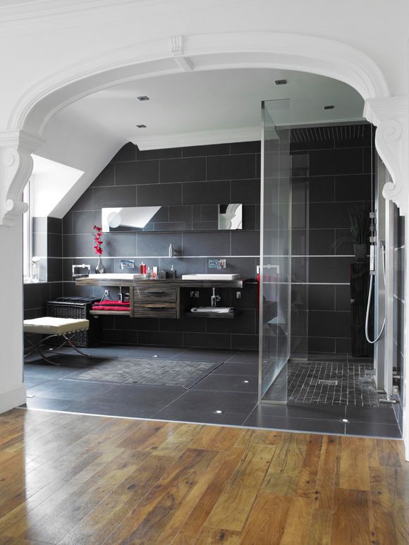 A shower room with a black tiled floor and a shower.