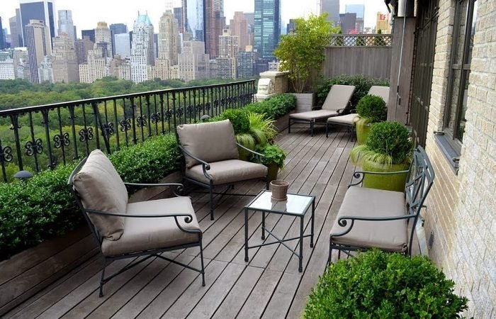 A paved balcony with furniture and a view of the city.