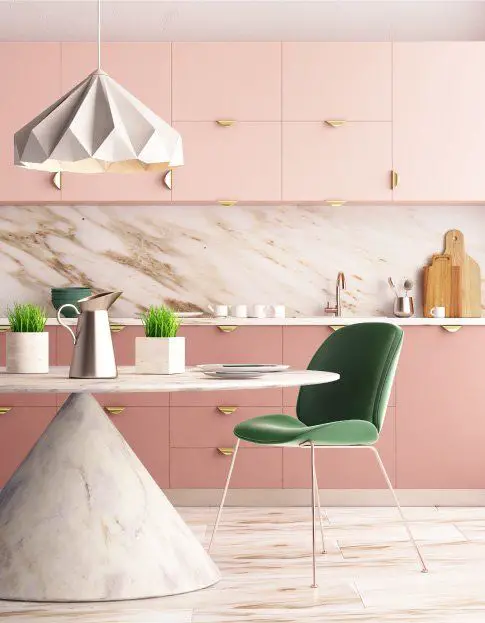 A pink kitchen with marble counter tops and green chairs is perfect for those who want to use pink in their kitchen design.