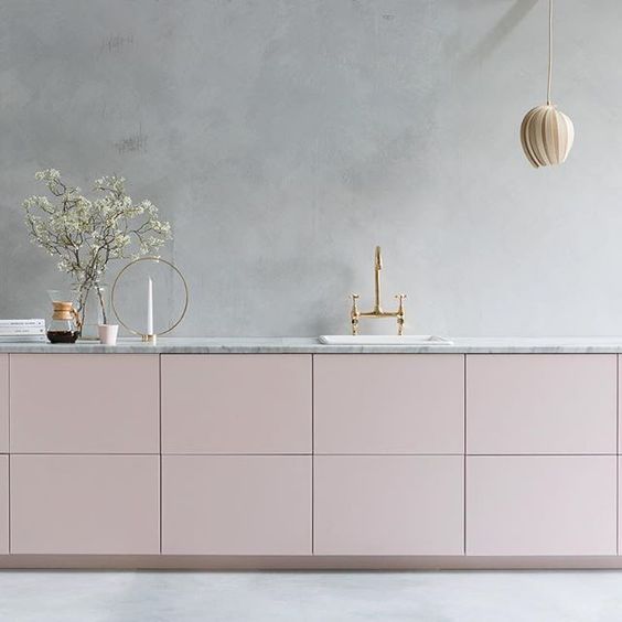 A kitchen with pink cabinets and a marble counter top, using pink.