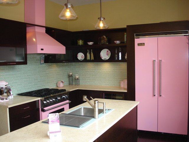 A kitchen with a pink refrigerator and black cabinets, showcasing the use of pink in the kitchen.