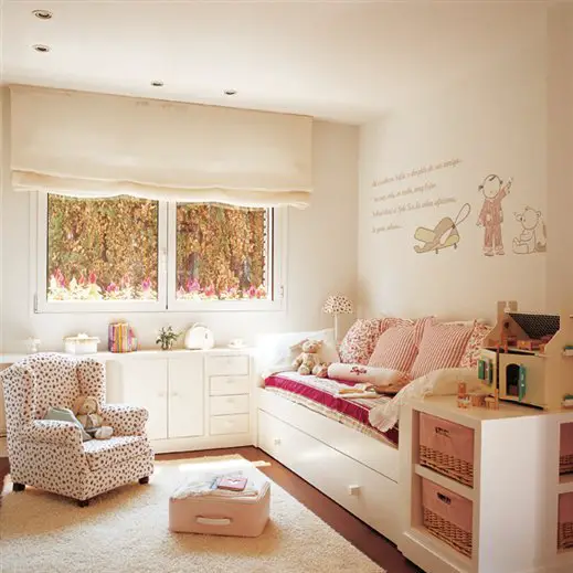 A kid's room with white furniture and a pink bed.