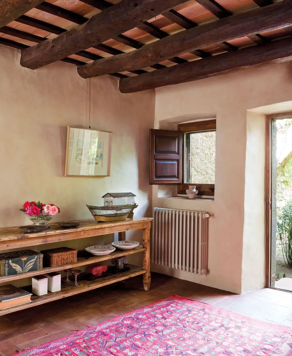 A room with wooden beams and woodworm-infested pink rug.