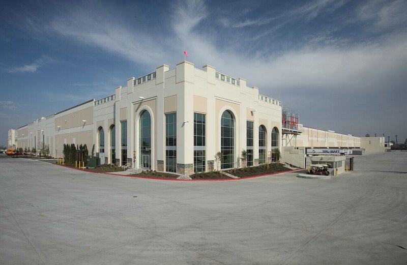 A large white Tilt-Up building with a parking lot in the background.