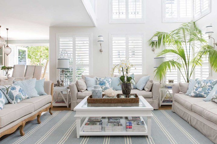 A living room with white furniture and blue shutters that brings Hamptons style vibes.