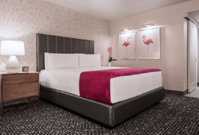 A tropical hotel room with a bed and a flamingo on the bed.