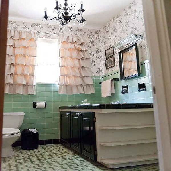 A renovated bathroom with green and white tile and a chandelier.