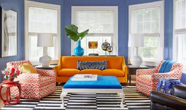 A living room with blue walls and orange leather furniture.