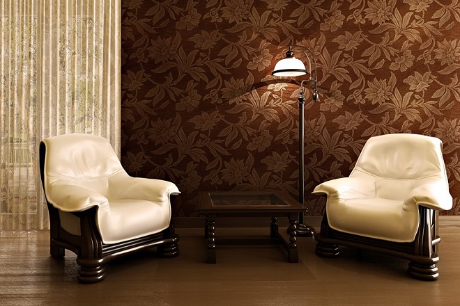 Two white chairs in a room in front of a brown wallpaper.