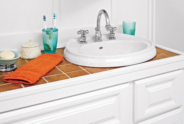 A bathroom renovation with a white sink and orange towels.