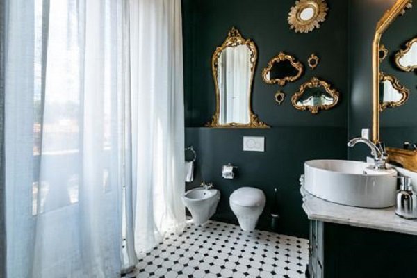 A Bathroom Renovation featuring black walls and gold mirrors.